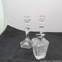 Pair of vintage clear glass candle holders with hexagonal bases alongside a vintage glass perfume bottle with a metal and glass atomizer top shown from a side angle.