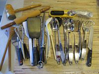 Wide view of assorted kitchen utensils including wooden rolling pins, meat tenderizer mallet, wire whisks, and spatulas.