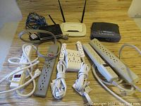 Lot assembly showing five power bars and three wireless routers on a table.