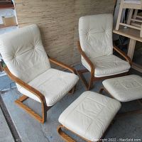 Two cream faux leather chairs and two footstools arranged