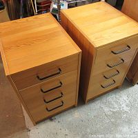 Photo showing both filing cabinets from an elevated angled side view, highlighting the wood-like finish and black handles on the drawers.