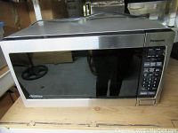 Front view of the Panasonic microwave oven showing stainless steel and black finish with inverter label on lower left.