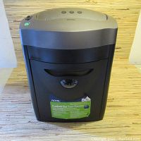 Front view showing Royal shredder with paper entry slot, control buttons, pull-out waste bin with handle and informational label.