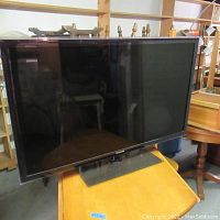 Front angled view of the Samsung 47 inch TV sitting on a table showing the screen and stand.