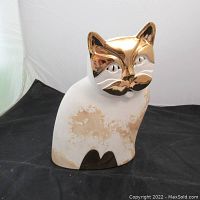 Front view of the ceramic cat decoration showing gold face and white body with age-related discoloration.