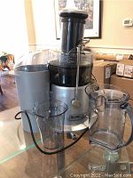 Full view of Breville Juice Fountain juicer with juice pitcher and juice cup on glass table.