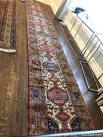 Full view of the carpet stair runner laid out on floor showing overall pattern, two sewn sections, and worn condition with some tacks