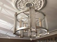 Full view of pendant chandelier hung from ceiling medallion, showing overall design and nickel finish
