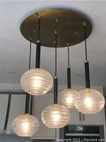 Oblique front view showing all five globes and black rods against ceiling