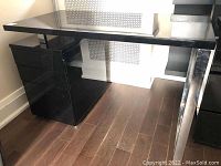 Front view of black and chrome desk with filing cabinet showing high-gloss surface and three drawer cabinet.