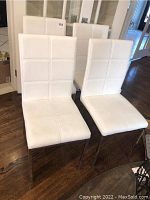 Front view of four white dinette chairs arranged together