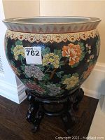 Front view of porcelain bowl on wooden stand showing exterior peony floral design and rim pattern