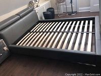 Full front view of grey upholstered bed frame with headboard and wooden slats