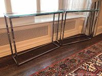 Two chrome console tables with glass tops, front view