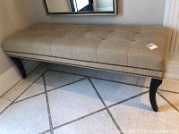 Front view of tufted bench showing upholstery, tufting and nailhead trim