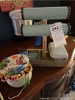 Photo showing jewelry holder stand, fabric-covered jewelry box with floral design filled with costume jewelry, and silver evening bag.