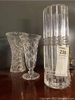 Three crystal glass vases with different cut patterns shown together on table.