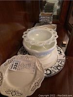 Stack of white ceramic dishes with black scroll decoration and a vintage white milk glass bowl on top.