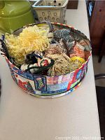Tin filled with assorted ceramic top tassels seen from above showing a variety of colors and textures