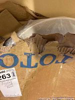 White Toto toilet seat partially visible in torn cardboard box with blue Toto branding.