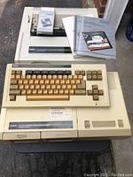 Photo of Coleco ADAM memory console with keyboard, data drive, and accompanying manuals on top.