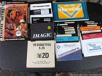 Photo of boxed game The Pharaoh's Curse, HomePak cartridge, various floppy disks and disk sleeves arranged on dark fabric surface.