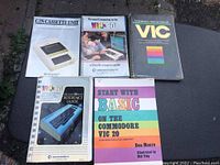 Photo showing five Commodore VIC-20 related books/manuals arranged on a dark surface, titles clearly visible.