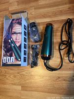 Hair dryer with power cord, attached round brush, and original box showing branding and product images.