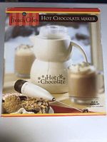 Box front view showing cream-colored hot chocolate maker with electric whisk and text logo.