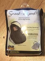 Original packaging of black infant car seat cover by Jolly Jumper showing product image and features.