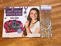 Photo of unopened Bead Seatings Jewelry Boutique kit box with image of assembled jewelry and bead mold toy, alongside unopened bag of silver rhinestones.