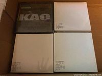 Top view of four packs of floppy disks in a cardboard box. One black translucent KOA pack sealed with 10 floppy disks, and three white cardboard packs of floppy disks labeled 5.25" MD2HD 10 PCS, two sealed and one open but unused.