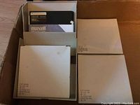 Box with Maxell MD2HD floppy disks and boxes of generic brand 5.25 inch floppy disks packed in white sleeves