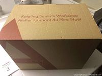 Cardboard box with 'Rotating Santa's Workshop' text, indicating the packaging.