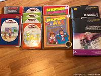 Multiple Atari software cartridges and educational titles with colorful cartoon-style labels, plus two large programming invite manuals with black covers and colorful graphics.