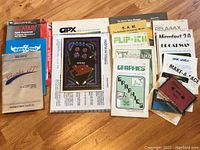 Photo of assorted Atari software instruction manuals, program guides, and documentation including Kangaroo, Grand Prix, GPX Pinball, and others, laid out in a fan shape.