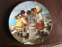 Front view of the round decorative plate depicting Arctic children and cats by a barrel on a rocky shore.
