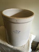 Front view of large beige stoneware crock with blue crown stamp on side showing no chips or cracks.