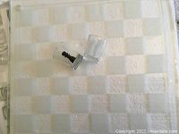 Close view of glass chessboard and shot glass chess piece with a black figurine inside