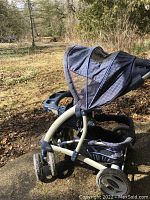 Side view of Grace baby stroller showing canopy partially open, front swivel wheel, and storage basket underneath.