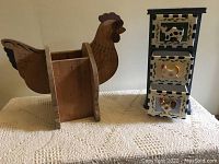 Wooden chicken-shaped planter and blue stacked spice stand with farm animal drawers on cream textured cloth.