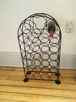 Front view of the black metal wine rack with one wine bottle present to show usage.