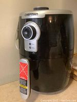 Front view of black Chefman air fryer with silver accents. Mechanical dial timer with knob on front.