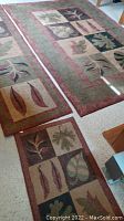 Photo showing three rugs arranged on floor, including a small throw rug, a runner, and a larger area rug each with matching leaf motifs in patchwork pattern.