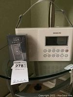 Photo showing Enence personal language assistant box in front of Sangean shower radio on glass table