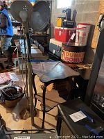 Photo showing two standing lamps with metallic round shades and flexible necks beside a small wooden table with scalloped edges.