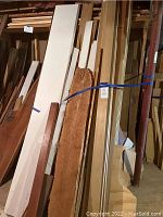 Image showing assorted lumber leaning against a wall including rough-cut natural wood slab and painted boards.