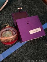 Glass ornament showing Philadelphia Eagles stadium with purple storage box labeled 'Vierge Studios'