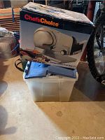 Box of Chef's Choice Premium Electric Food Slicer 615 shown with a white plastic container in front.