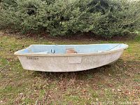 Side profile of the Ensign dinghy showing white exterior hull with Ensign branding and blue interior with wooden bench.